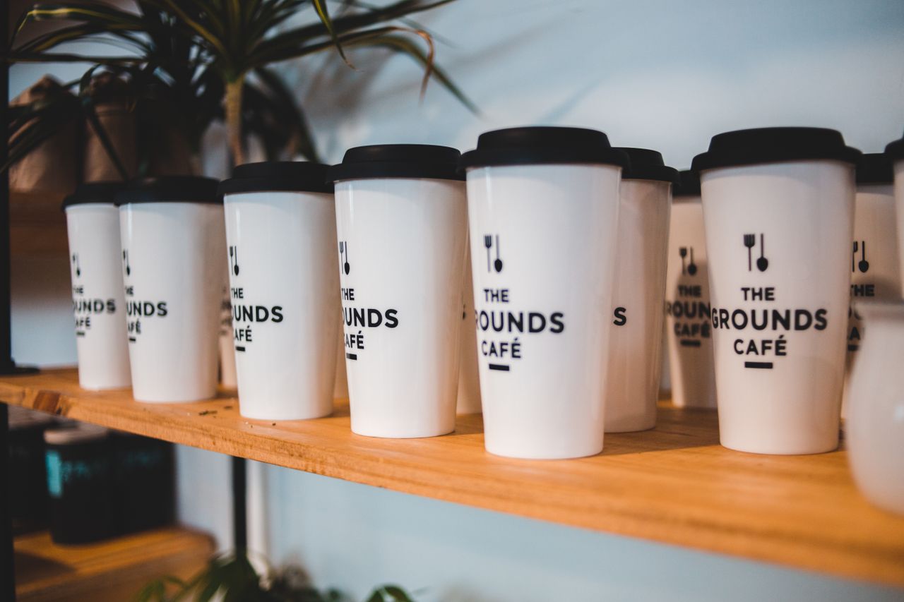 services-03 Designed white for coffee with black silicone lids and cutlery symbols on shelf for sale in coffee shop