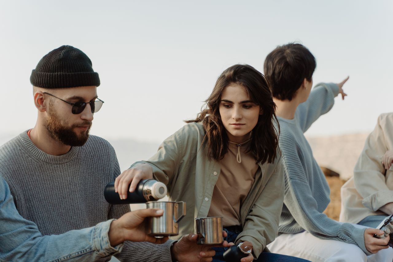 gallery-1 A group of friends enjoying hot drinks outdoors, symbolizing relaxation and togetherness.